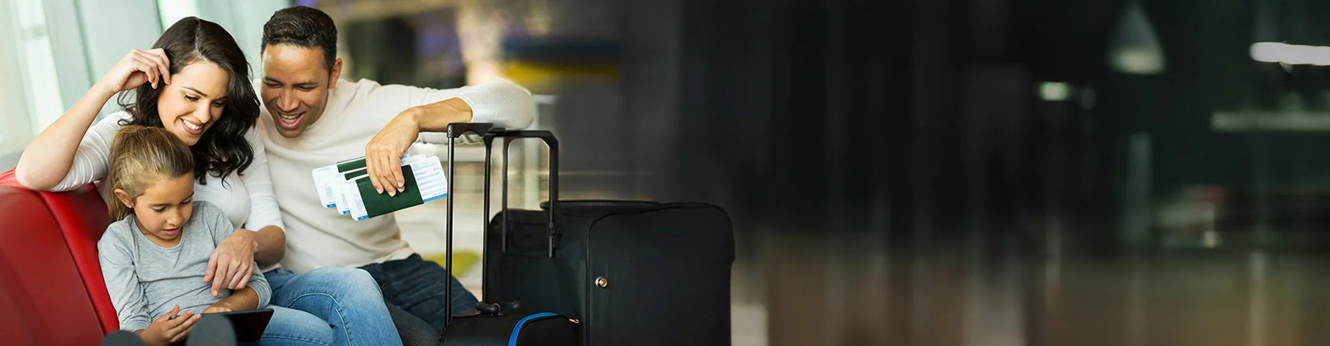 Family with luggage and boarding passes sitting at an airport terminal