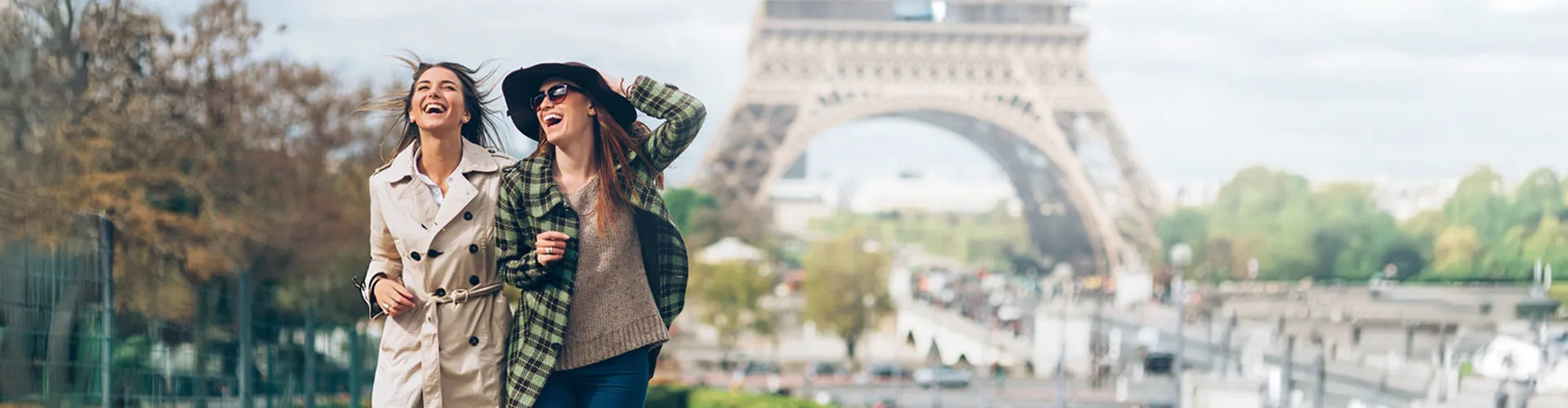 Two women laughing and walking outdoors with the Eiffel Tower in the background